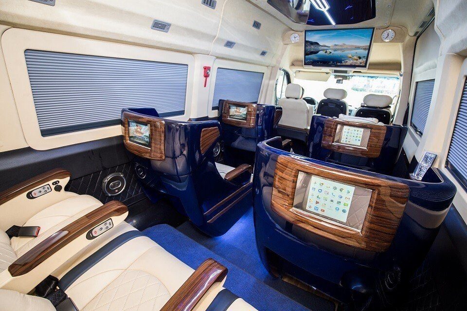 Khoang nội thất Limousine Quỳnh Thanh: ghế ngả bọc sáng màu, bàn ốp gỗ và màn hình